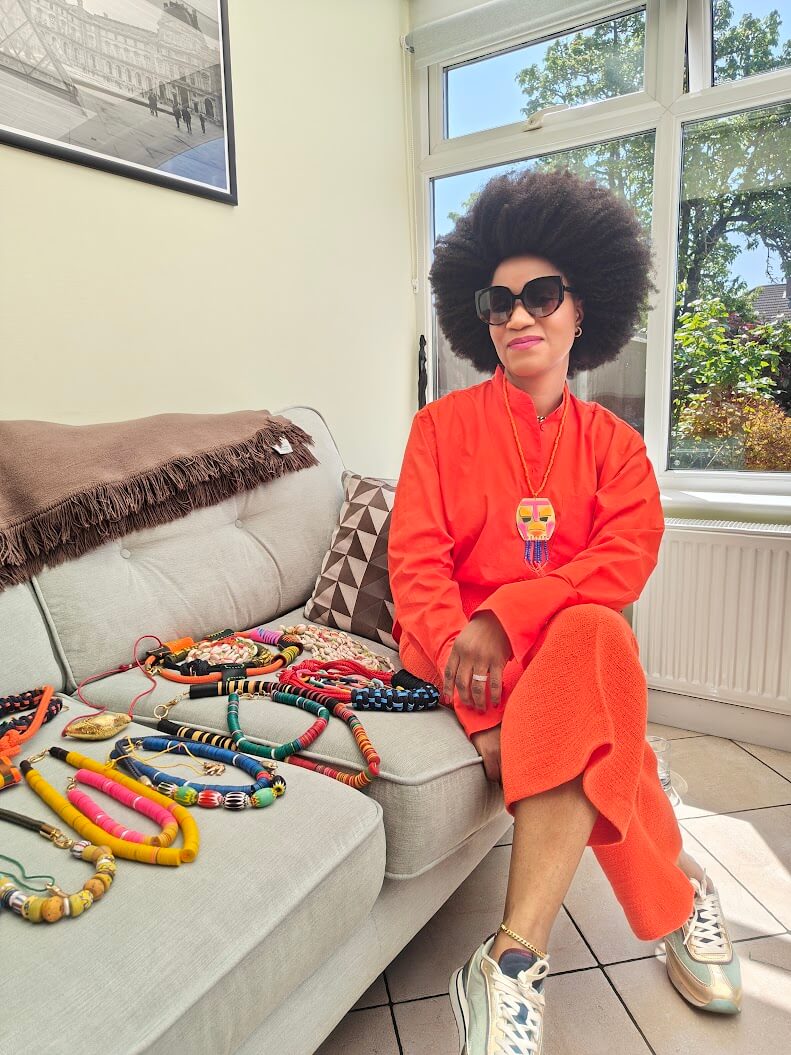 Ghanain Founder, sitting on couch displaying bold artisan jewellery collection.