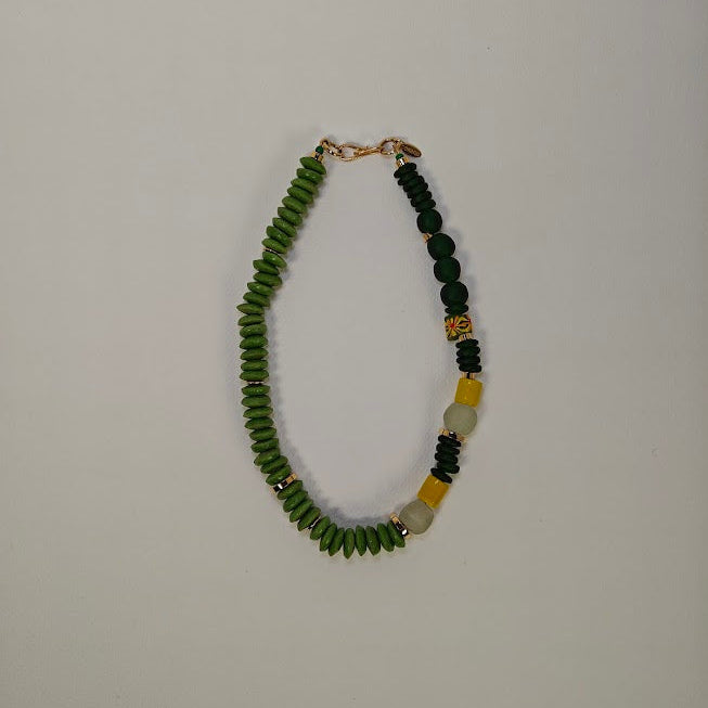 Necklace with green, dark green, yellow and gold plated beads on a light gray background