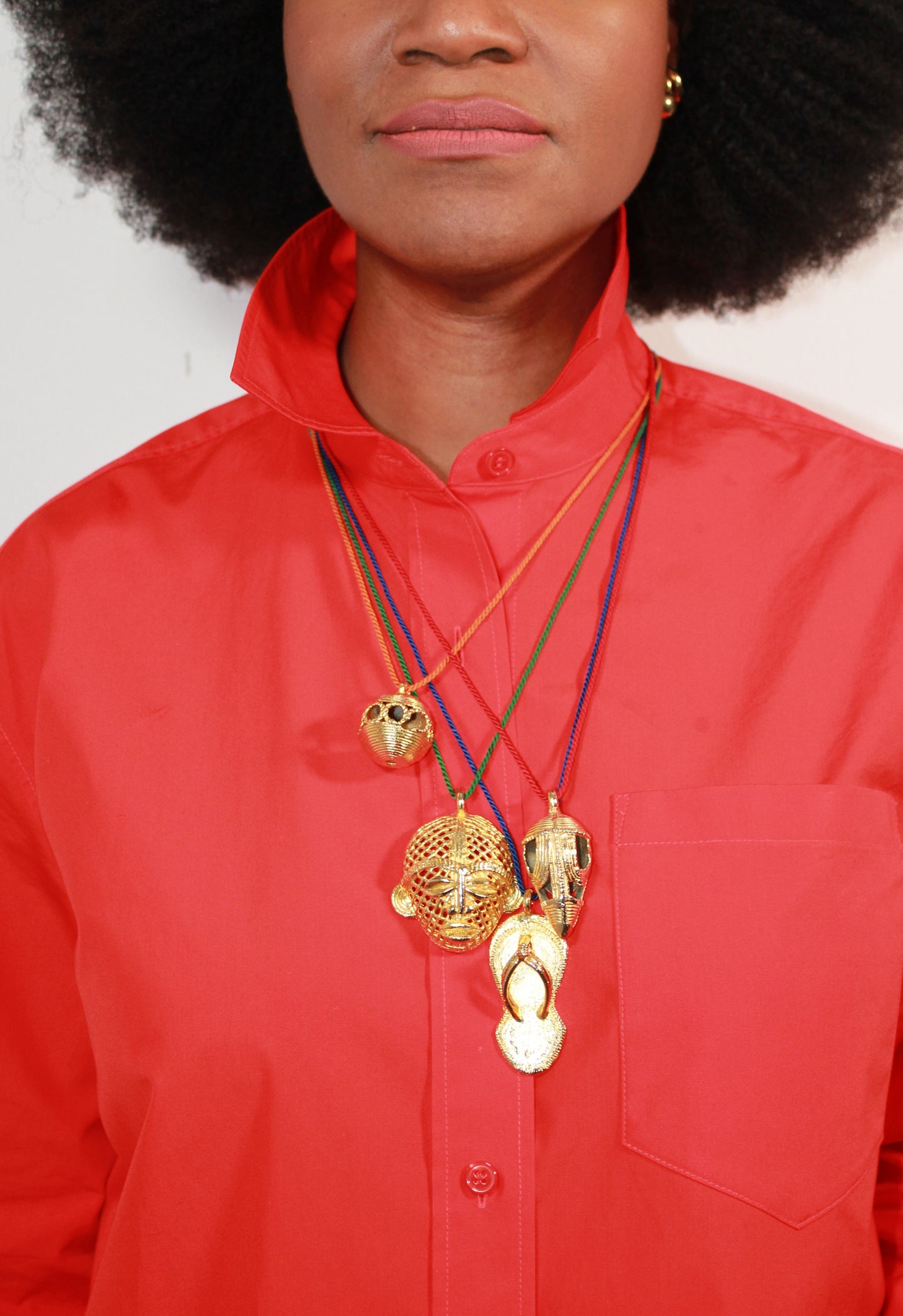 Person wearing a red shirt with gold pendent necklaces