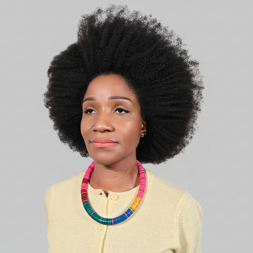 Woman with an afro wearing a colorful necklace against a light grey background
