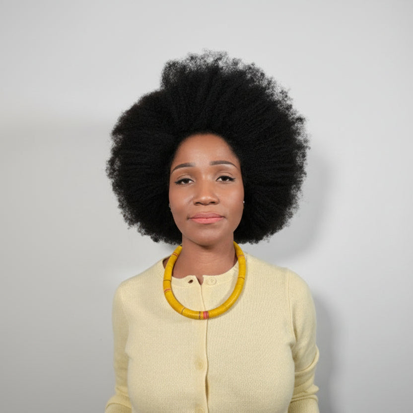 Woman wearing a yellow sweater and necklace against a plain background