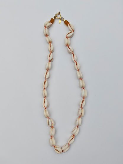 Long length cowrie shell and glass bead necklace on a white background