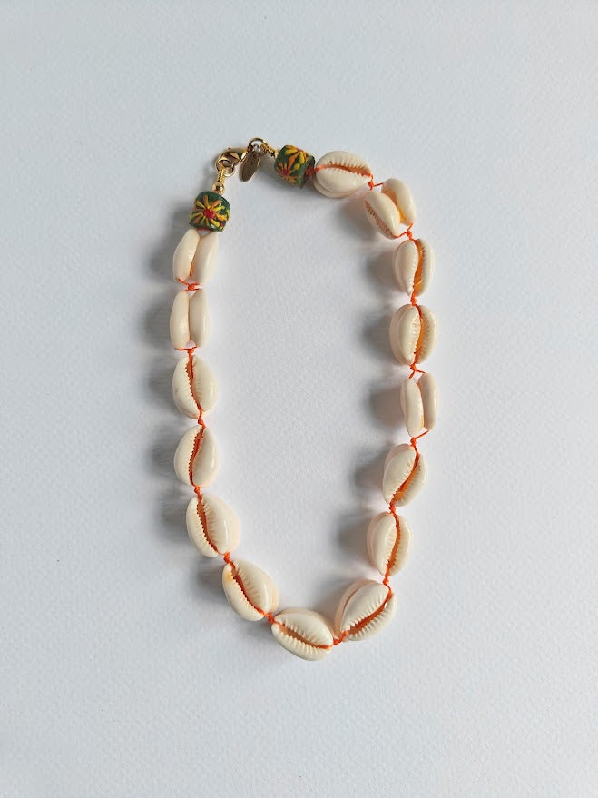 Cowrie shell necklace with a colourful recycle glass beads near the clasp on a light gray background