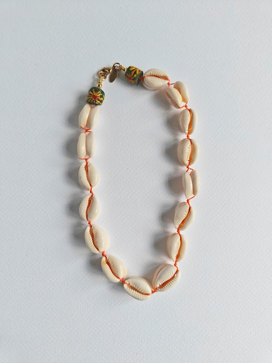 Cowrie shell necklace with a colourful recycle glass beads near the clasp on a light gray background