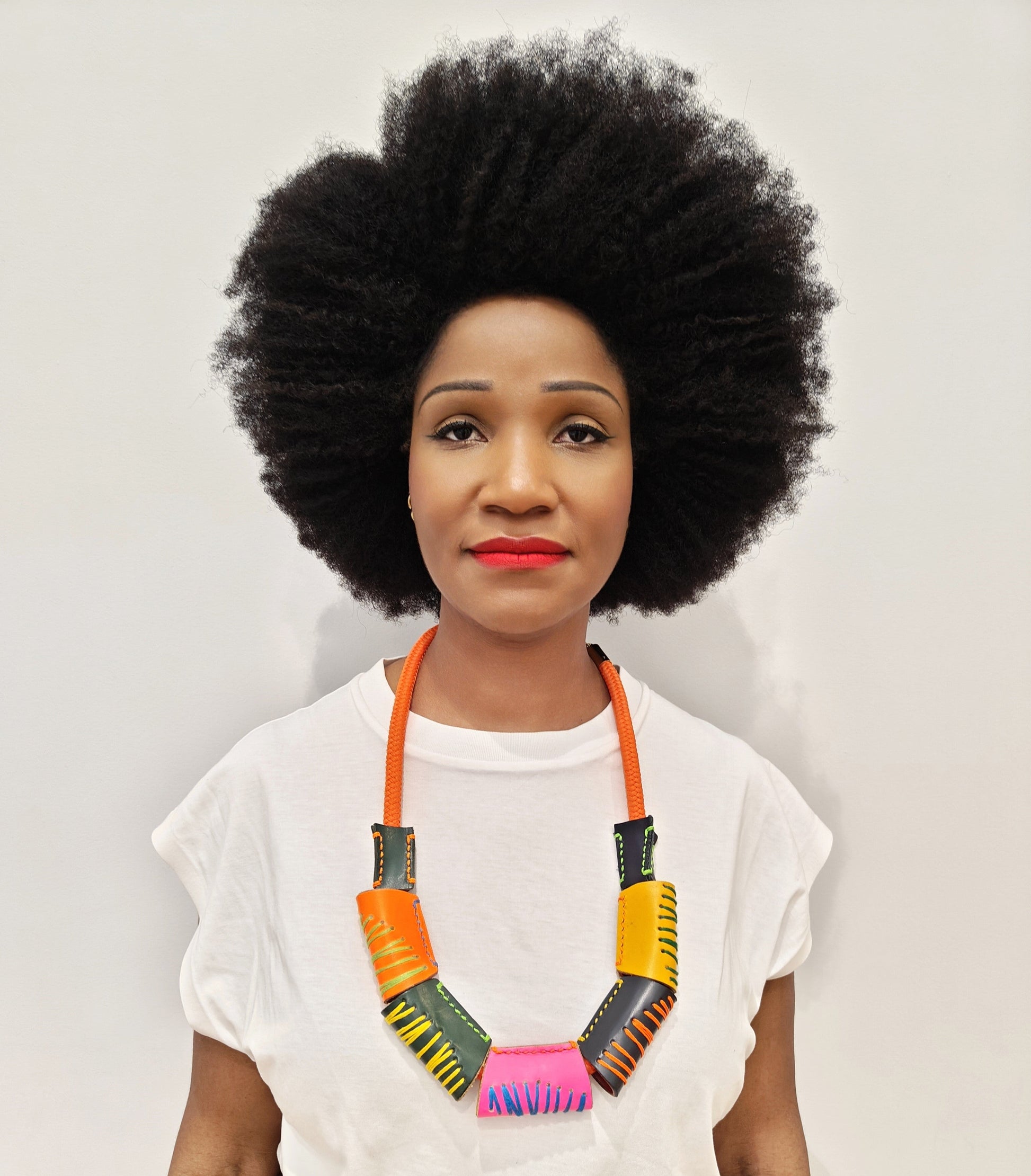 Woman wearing a handcrafted colorful leaather bead necklace against a plain background