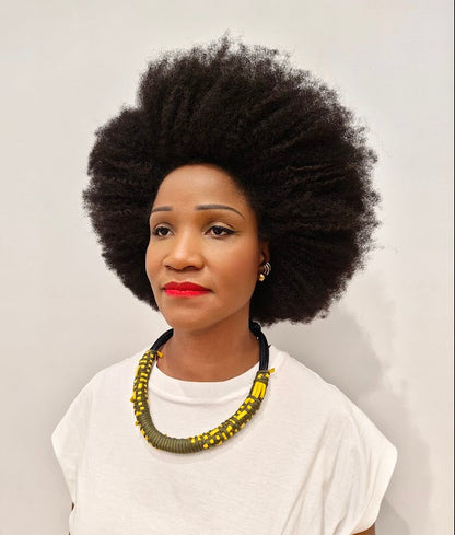 Woman with afro wearing a rope and leather necklace with a white tee shirt