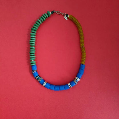 Necklace with green, blue, and yellow beads on a red background