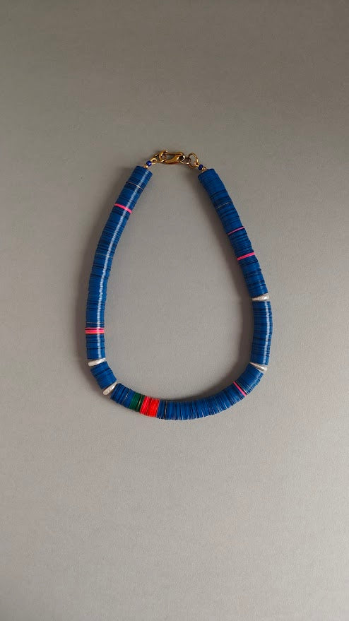 Necklace with blue, red, green,pink beads and freshwater pearls on a gray background