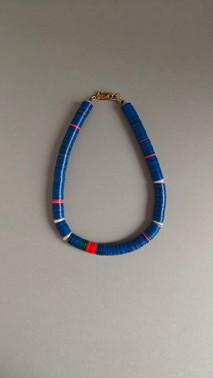 Necklace with blue, red, green,pink beads and freshwater pearls on a gray background