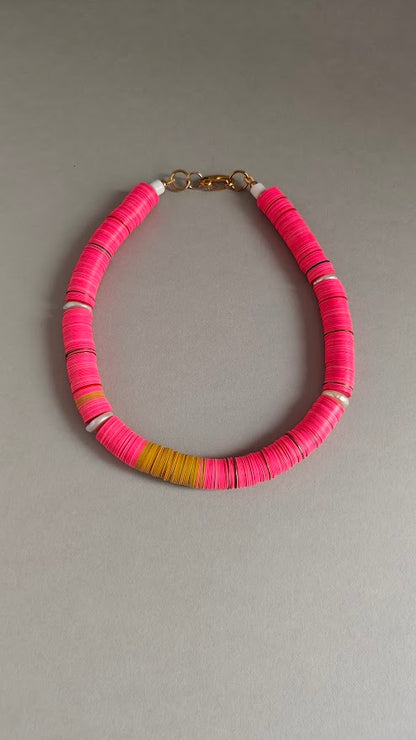 Necklace with pink and yellow beads  and freshwater pearls on a gray background