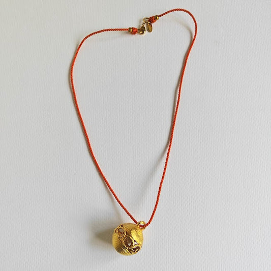 Textured brass ball pendant on orange cotton cord, 31 cm, gold-plated clasp

