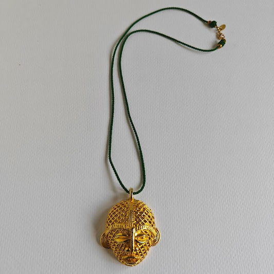 Gold pendant necklace on a green cord against a light gray background