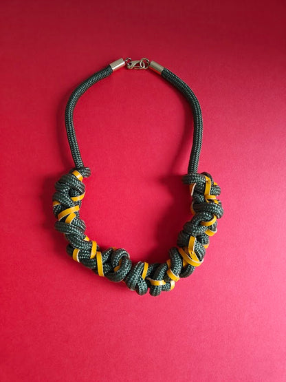 Chunky khaki green rope and leather necklace on red background