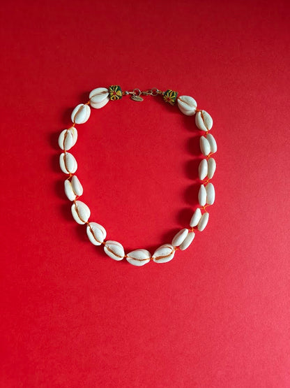 Cowrie shell necklace with  colourful recycle glass beads near the clasp on a redbackground