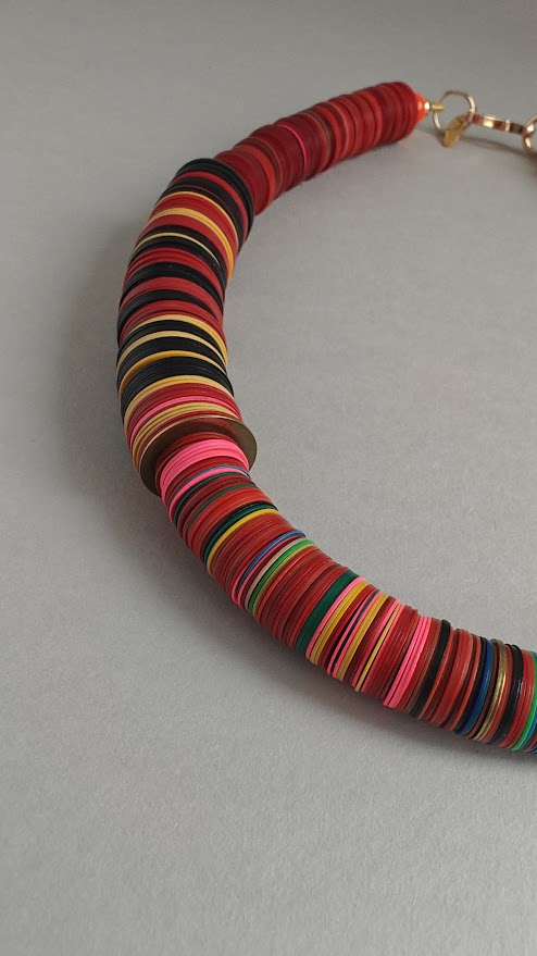 Close up section of a colorful beaded necklace on a gray background