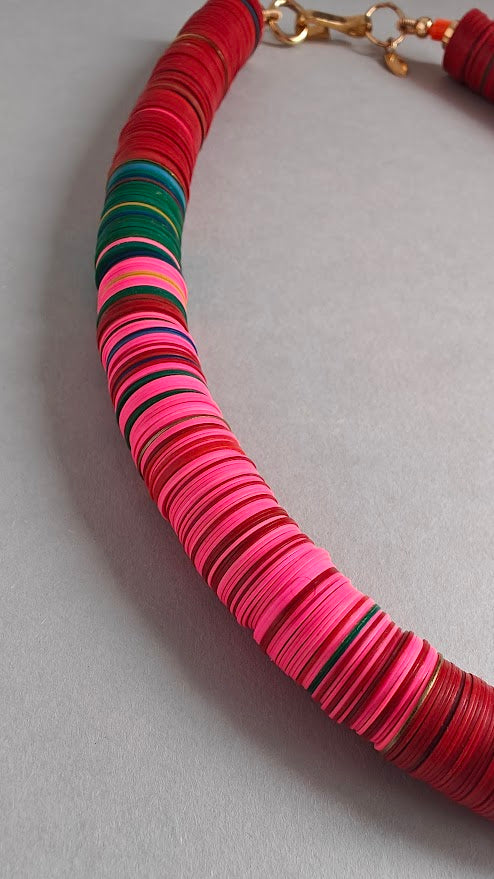 Colorful necklace with red, wine,pink, blue,and green beads on a grey background