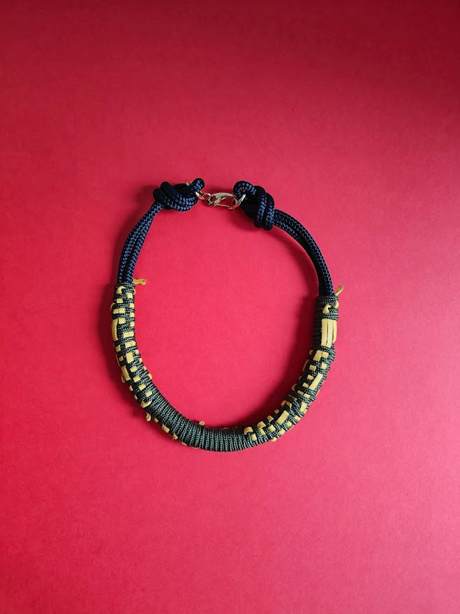 Khaki green and navy rope necklace with navy, woven with yellow leather a red background 