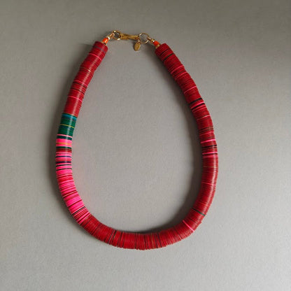 Necklace with red, wine, pink and green beads on a gray background