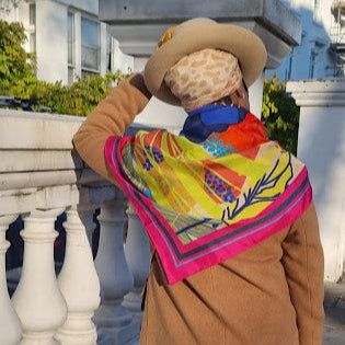 Model wearing large square silk scarf styled as a wrap, statement African-inspired print