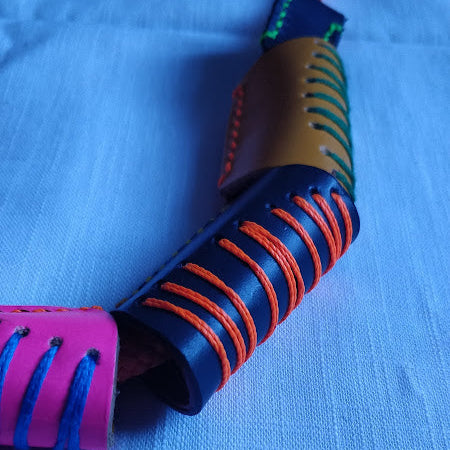 Close-up of colourful leather beads and cotton yarn stitching, gold-plated clasp