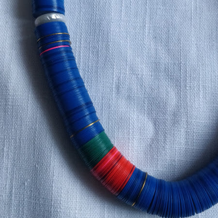 Close-up of vinyl bead blocks with pearl and brass disc details on handcrafted necklace